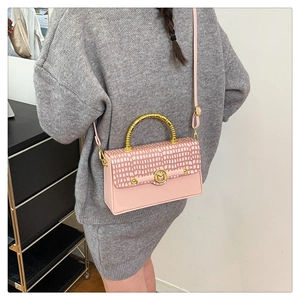 Detail of pink PU box bag with crocodile texture, golden M-buckle and metal handle