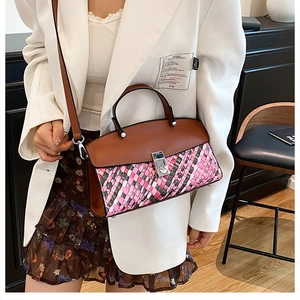 Detail of color-block woven handbag with brown leather trim and silver metal buckle