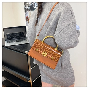 Close-up of brown croc-embossed leather bag with golden metal handle and M logo buckle