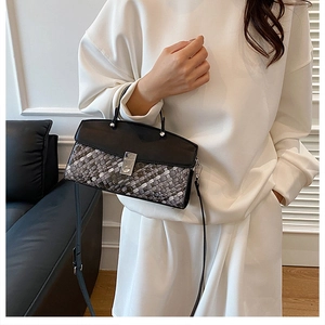 Detail of woven texture handbag with silver metal buckle on a black leather flap