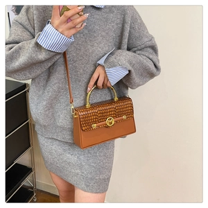 Detail of premium PU leather box bag with gold M buckle and spiral metal handle