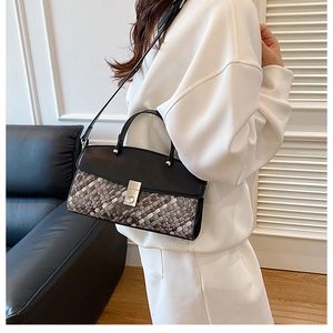Detail of grey woven texture handbag with black leather flap and metal twist lock