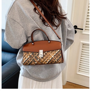 Detail of woven texture and brown leather flap on a crossbody bag with a metal lock