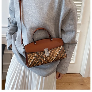 Detail of woven texture handbag with brown leather trim and silver metal lock closure