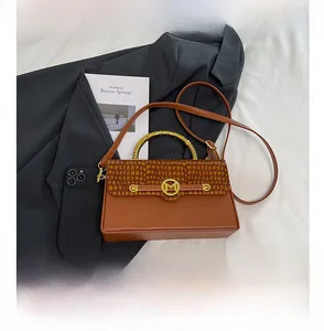 Detail view of brown PU leather bag with crocodile texture lid and golden M-buckle