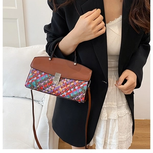 Close-up of a woven pattern handbag with brown leather flap and silver metal turn-lock