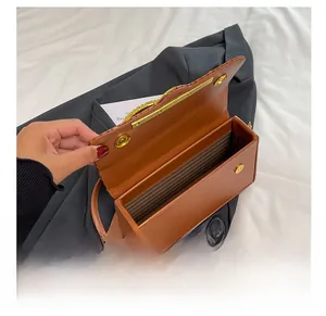 Detail view of the brown PU box bag interior featuring striped lining and gold hardware