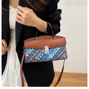Detail of multi-color woven handbag with brown leather flap and silver metal lock closure