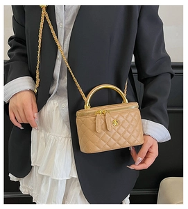 Détail du mini sac boîte beige matelassé avec fermoir fleur dorée et bandoulière chaîne