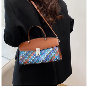 Detail of woven texture handbag with leather trim and silver clasp worn with a black suit