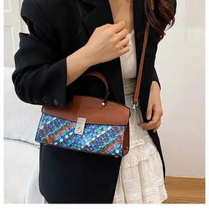 Detail of colorful woven texture and brown leather flap on a crossbody bag with silver buckle