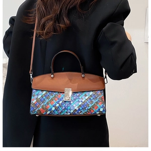 Detail of colorful woven texture handbag with brown leather handle and silver metal lock