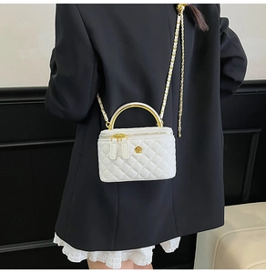 Détail du mini sac boîte matelassé blanc avec fleur dorée et poignée en métal