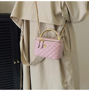 Sac boîte matelassé rose chic avec poignée dorée porté sur un trench-coat beige