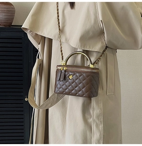 Détail d'un sac boîte matelassé marron foncé avec poignée métal et bandoulière chaîne