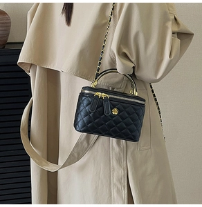 Détail du mini sac boîte en cuir noir matelassé avec camélia doré et bandoulière chaîne