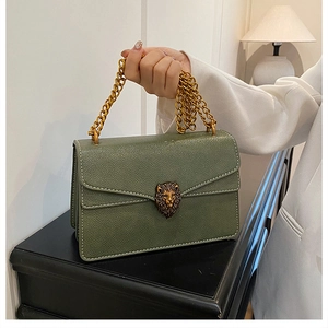 Detailed close-up of dark green lychee leather bag with golden lion head emblem clasp