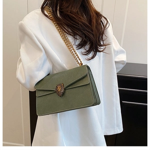 Detail of olive green lychee leather handbag with golden lion head buckle and chain