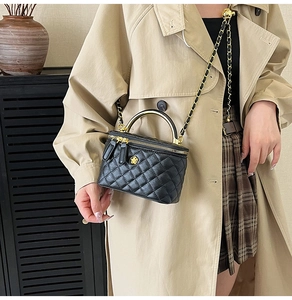 Détail du mini sac boîte noir matelassé avec poignée dorée et bandoulière en chaîne