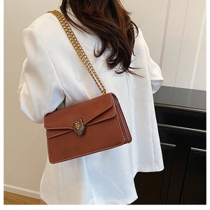 Detail of brown lychee leather shoulder bag with gold lion head buckle and chain strap