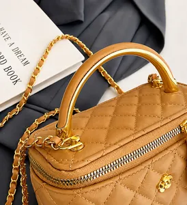 Détail d'un sac à main en cuir matelassé marron avec chaîne dorée et poignée pratique