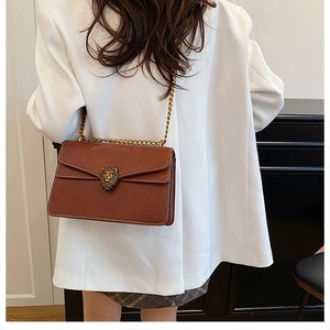 Detailed close-up of brown textured leather shoulder bag with golden lion head buckle
