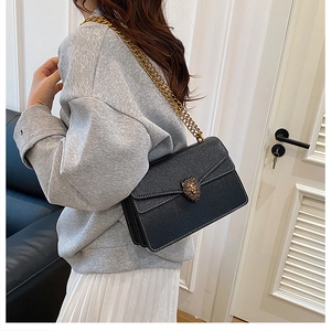Side view of black lychee leather crossbody bag with vintage golden lion head buckle