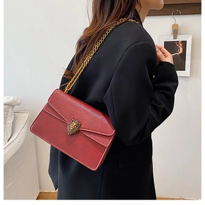 Detail of burgundy lychee leather chain bag with vintage gold lion head buckle decoration
