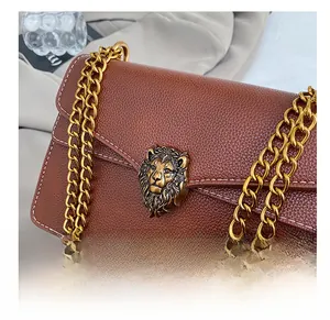 Close-up of brown pebbled leather bag with vintage gold lion head buckle and chain