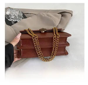 Detail of brown lychee leather bag with gold chain strap and lion head buckle