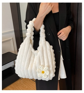 Detail of white plush tote bag featuring soft faux fur texture and small daisy charm