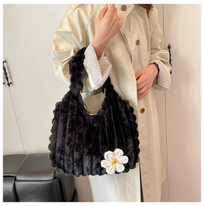 Detail of black plush tote bag featuring vertical texture and a small white daisy flower