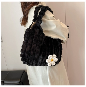 Detail of black plush tote bag featuring a white crochet flower and ribbed texture