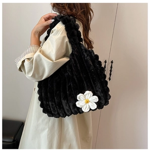 Close-up of black plush tote bag featuring a large crochet flower and striped faux fur texture