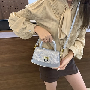 Detailed view of the luxury snake skin texture and metal D logo on this women box bag