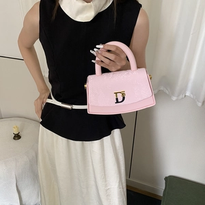 Detail of pink handbag featuring snakeskin texture flap and gold D-shaped buckle