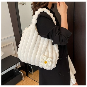 Detail view of white plush tote bag with knitted flower and pom-pom shoulder strap texture