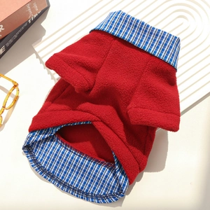 Detail of red fleece pet sweater with blue plaid trim on white textured background