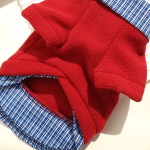 Detail of red fleece pet sweater with blue and white plaid collar and hem patchwork
