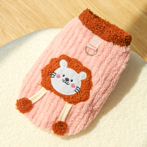 Detail of pink fleece pet vest featuring a lion patch, plush pom-poms, and metal D-ring hook