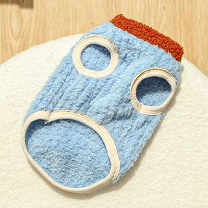Detail of blue fleece pet vest with orange sherpa collar on a soft white cushion
