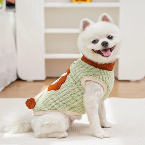 Detail of warm green fleece pet vest with orange plush trim on a small white dog