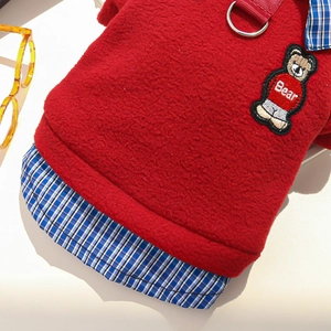 Detail of red fleece pet vest featuring blue checkered trim and a cute bear embroidery