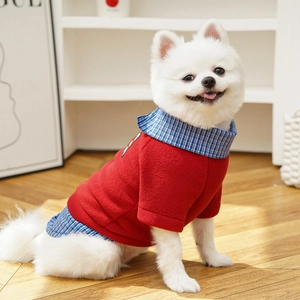 Detail of red fleece pet sweater with blue plaid collar on a small white dog