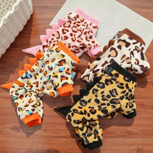 Detail of leopard print pet dinosaur onesies in four colors on a wooden floor