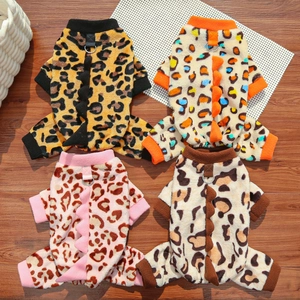 Detail of four leopard print pet jumpsuits with dinosaur spikes and D-ring on wood floor