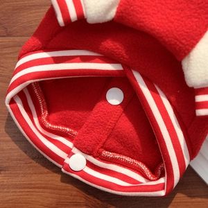 Macro detail of red fleece pet jacket featuring white snap buttons and striped ribbing