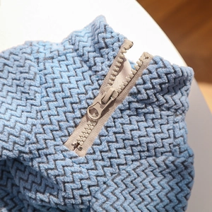 Macro detail of sky blue knitted pet jacket with wavy texture and durable metal zipper
