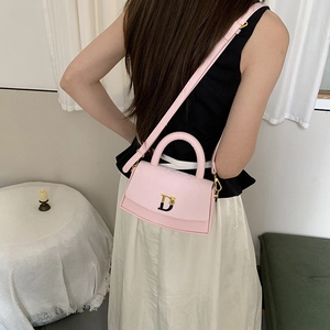 Detailed macro view of pink faux leather box bag with gold metal D-logo buckle