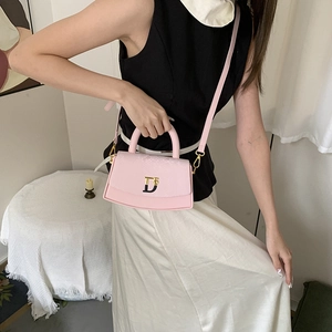 Detail view of a pink box bag featuring a TD metal logo and adjustable leather strap